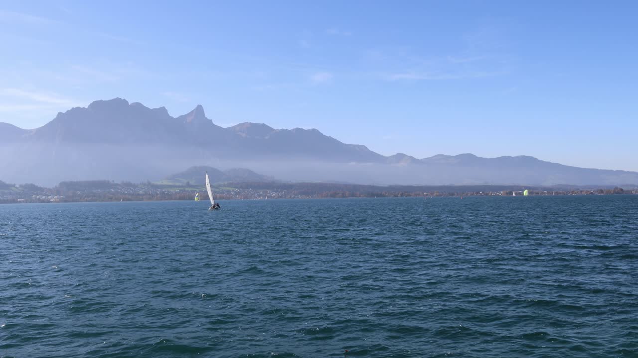 Sailboat sailing across a large lake towards the mountains, establisher