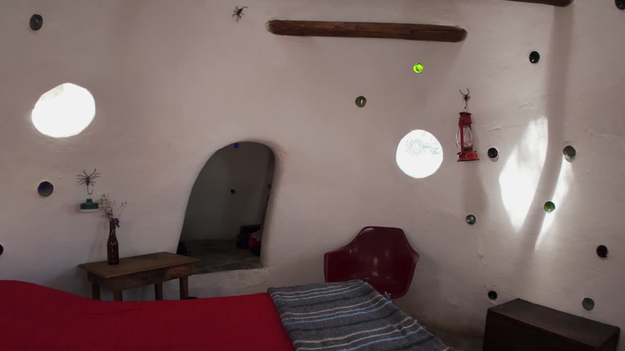 Interior view of a dome-shaped bedroom with red bed and arched doorway