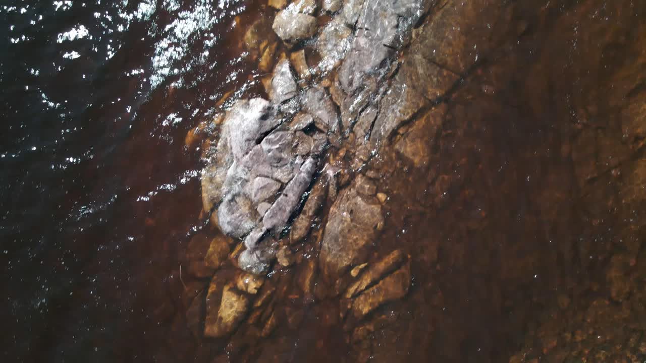 Rocce sommerse in acqua limpida con riflessi sulla superficie.