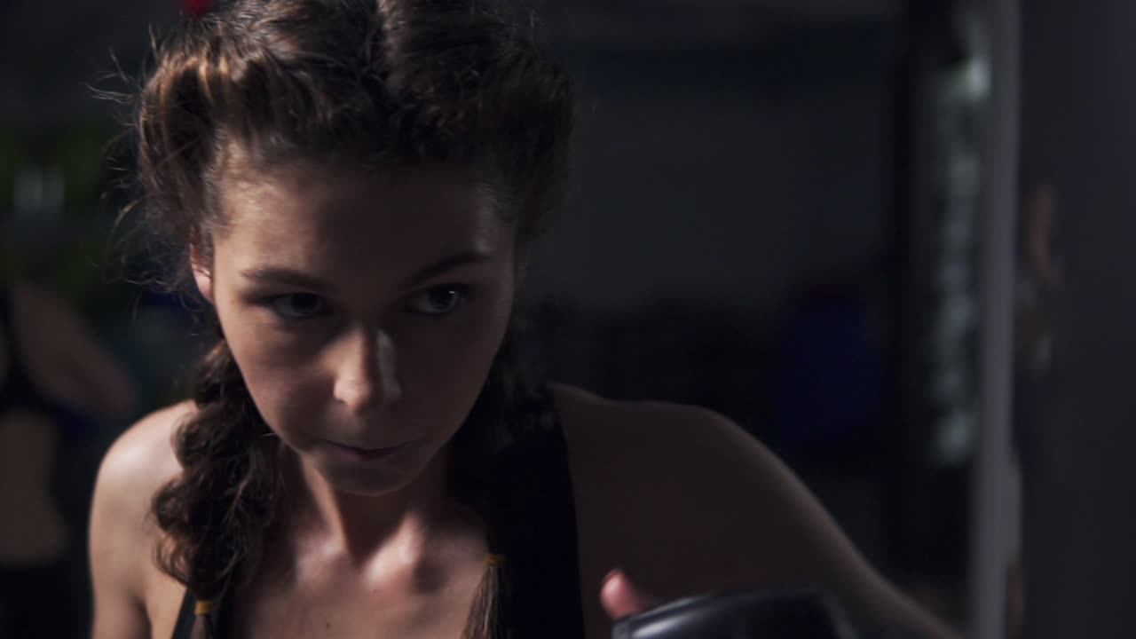 vista de cerca de una mujer joven con guantes de boxeo entrenando con un saco de boxeo en un club de boxeo. disparo en cámara lenta