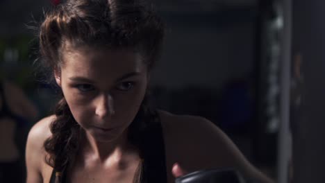 vista de cerca de una mujer joven con guantes de boxeo entrenando con un saco de boxeo en un club de boxeo. disparo en cámara lenta