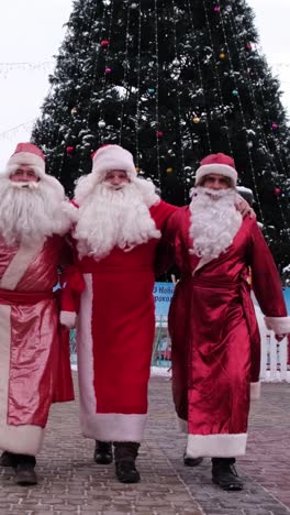 three men as santa pose joyfully by a decorated christmas tree three men in santa claus outfits pose joyfully in front of a decorated christmas tree embodying the cheerful spirit of the season
