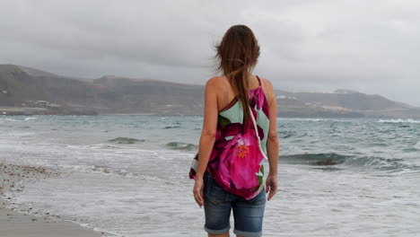 Cinematic-shot-at-dawn-of-a-woman-walking-along-the-shore-of-Las-Canteras-beach