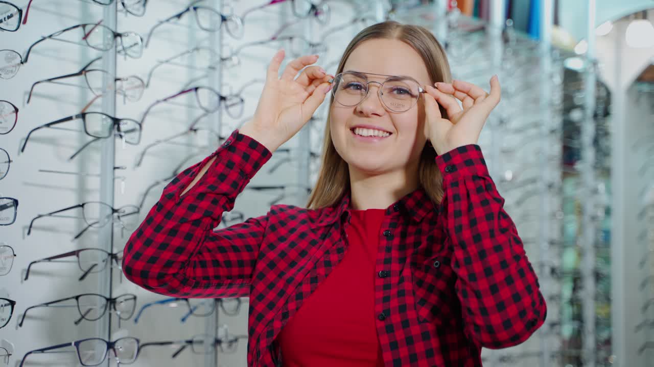 Portrait of a happy woman trying on trendy eyeglasses. Smiling female buyer choosing new glasses and posing on camera in optic store.