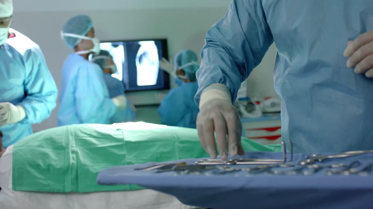 sección media de un cirujano biracial preparando instrumentos quirúrgicos en el quirófano, cámara lenta