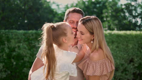 Smiling-father-holding-daughter-on-hands.-Pretty-girl-kissing-mother-in-nose