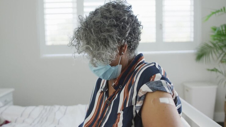African american senior woman wearing face mask showing covid vaccinate passport