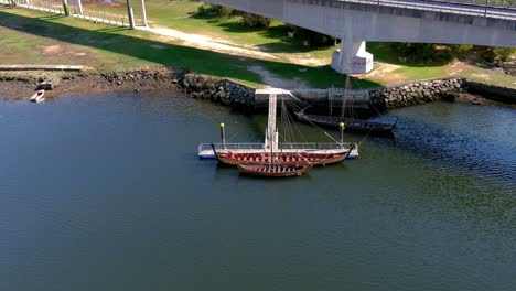 An-intrigued-person-at-the-jetty-boards-a-Viking-rowing-boat-on-display-on-display-on-the-Ulla-River,-sunny-summer-afternoon,-overhead-drone-shooting