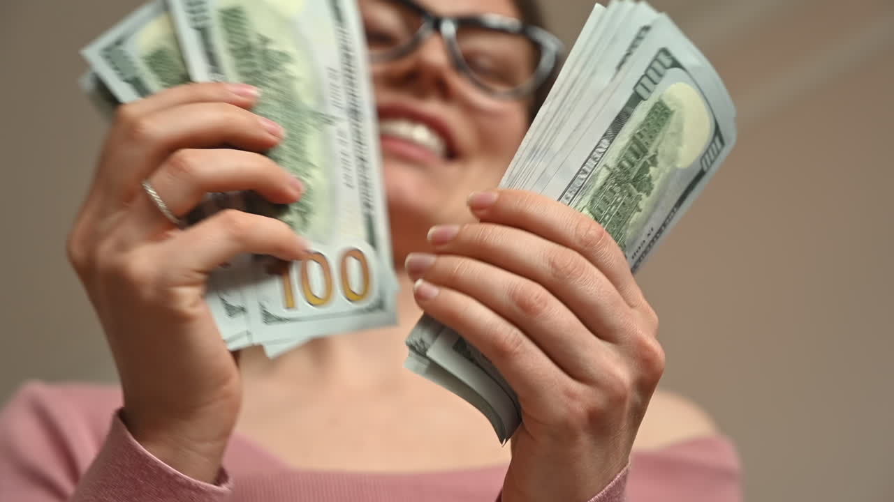 Smiling woman counting multiple one hundred dollar bills in her hands