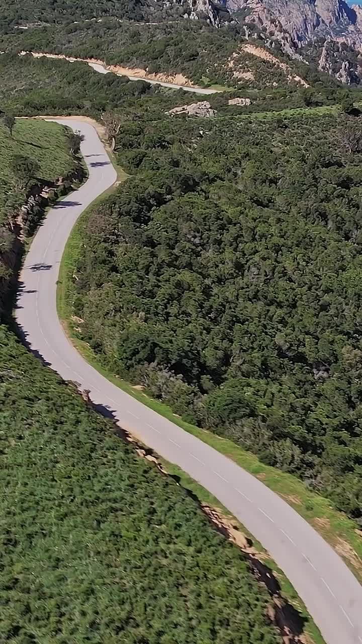 Strada tortuosa tra le colline in Corsica, Francia, durante una giornata di sole