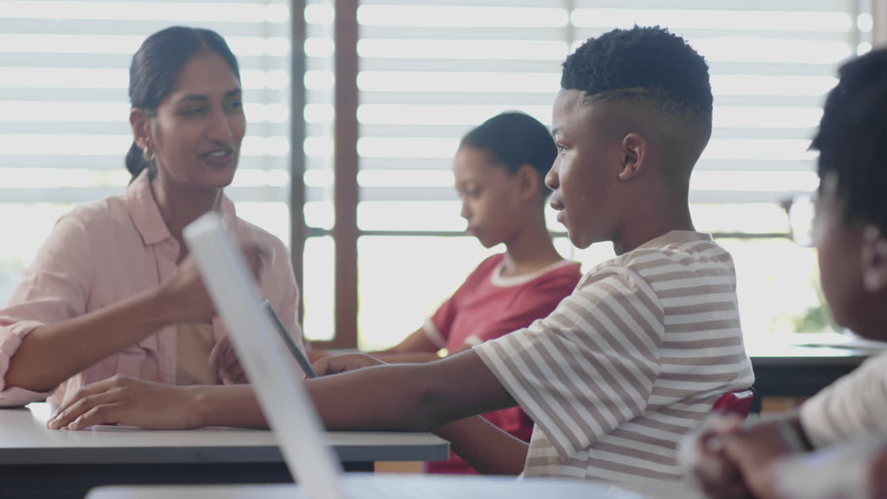In school, teacher helping students with laptop in classroom, engaging in learning
