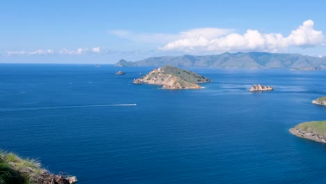 Speed-boat-moving-through-blue-ocean-with-idyllic-tropical-islands-scattered-in-Komodo-National-Park,-East-Nusa-Tenggara,-Indonesia