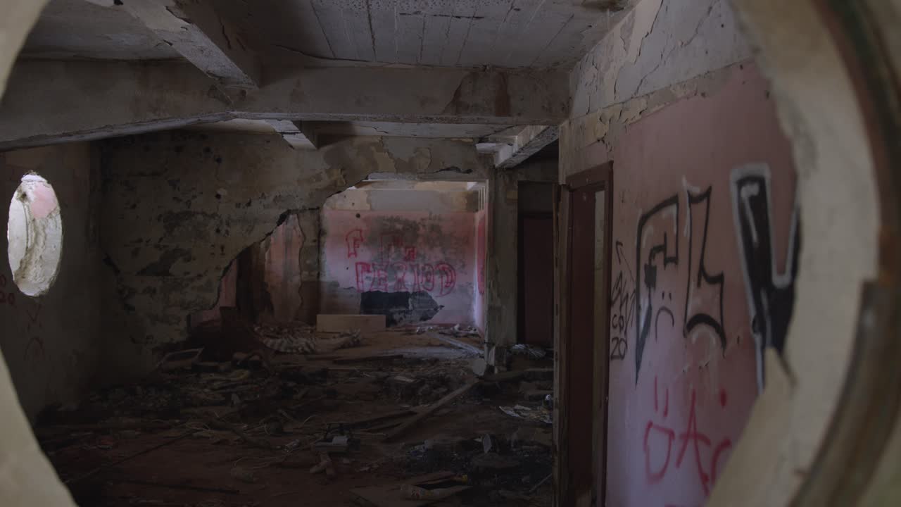 Camera passing through a circular hole. Suspenseful handheld dolly shot inside of a dissipated building.