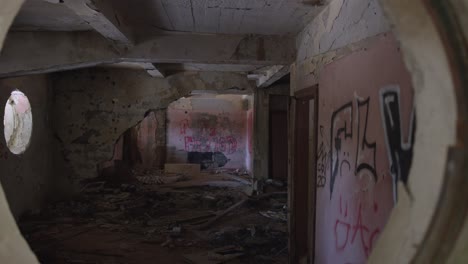 camera passing through a circular hole. suspenseful handheld dolly shot inside of a dissipated building.