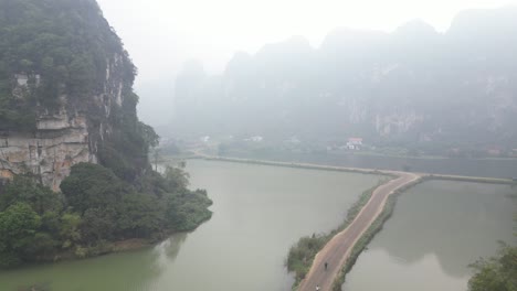 drone shot of biker on a bike path through swampy causeway in the mountainous region of ninh ninh in northern vietnam