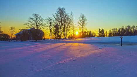 Timelapse--sunrise-over-snowy-field-with-sun-rays-through-trees