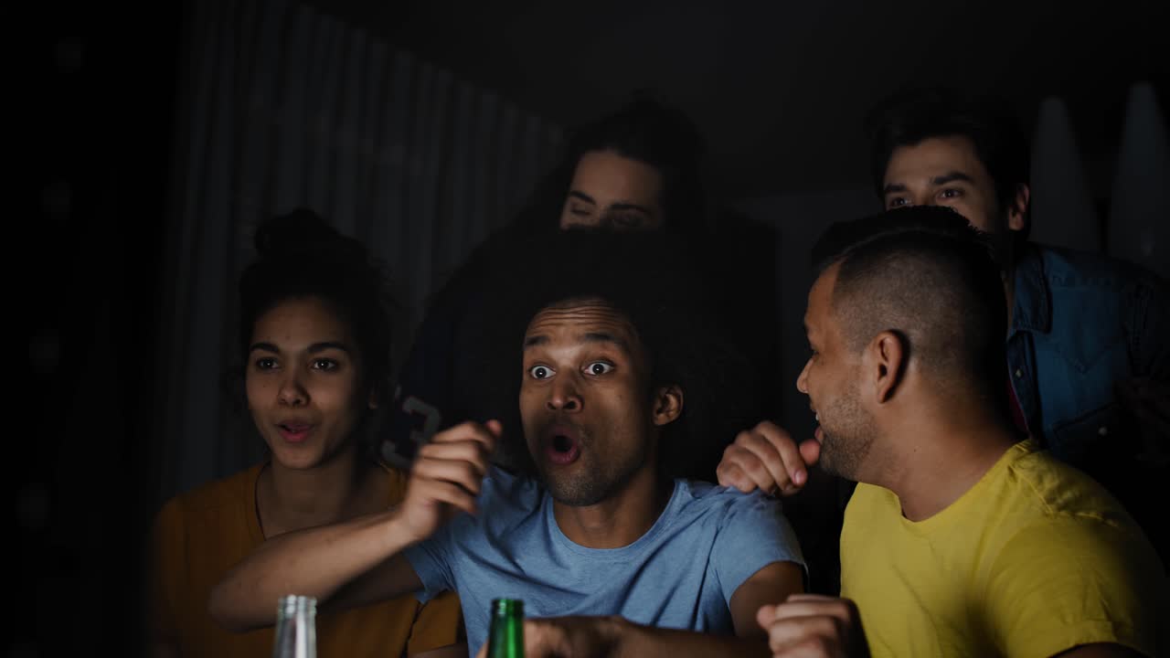 video de amigos emocionados viendo la televisión por la noche