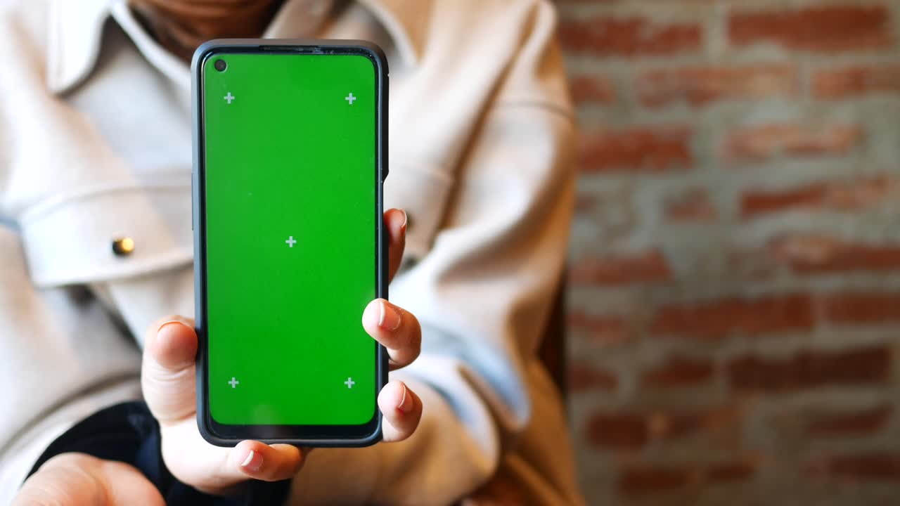 mujer sosteniendo un teléfono inteligente con pantalla verde