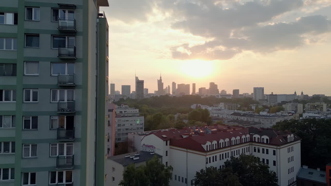 Apartment block close up revealing Warsaw city skyline, Poland, aerial view at sunset