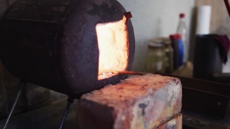 close up hands of caucasian male knife maker in workshop using oven