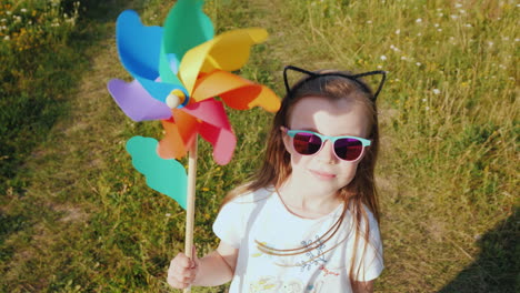 portrait of a stylish little girl with a toy windmill in her handst