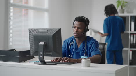 doctor's online medical consultation: african american physician making a conference video call with a patient on a desktop computer.