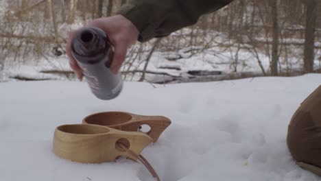 black balsam poured in kuksa wooden cups on snow