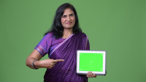 mature beautiful indian woman showing digital tablet and pointing finger