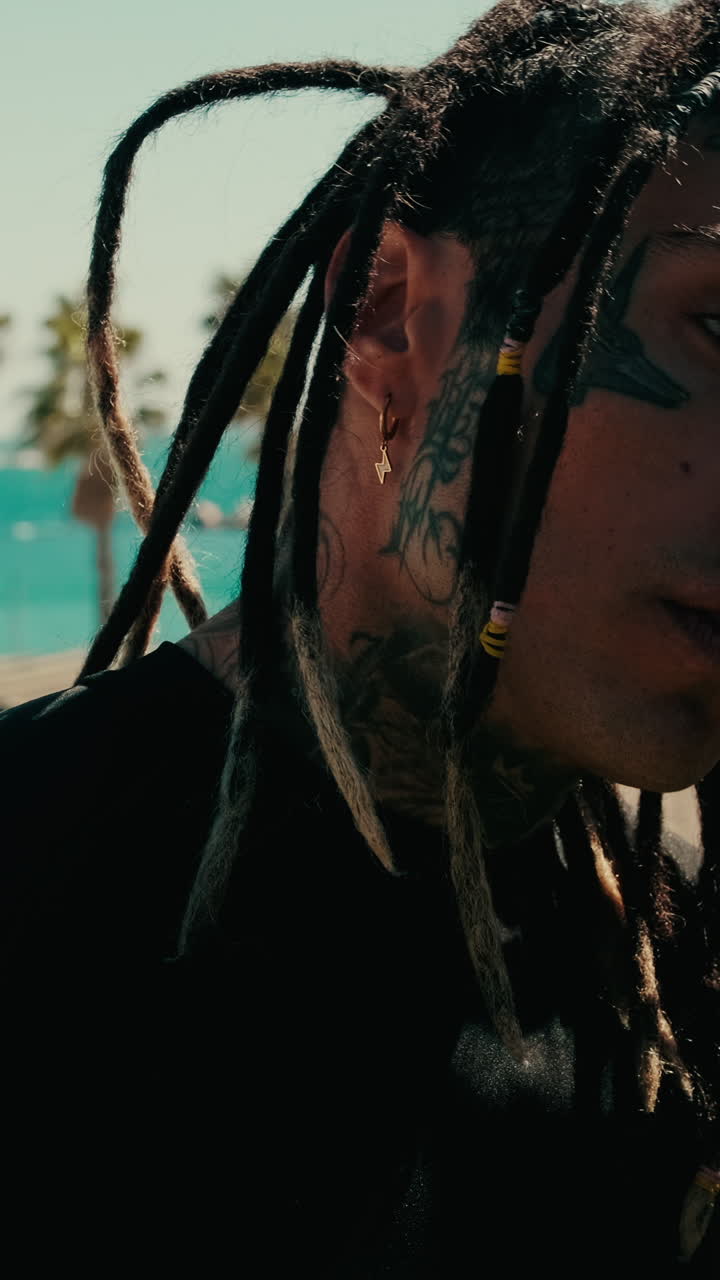 Thoughtful Man with Dreadlocks and Face Tattoos Outdoors