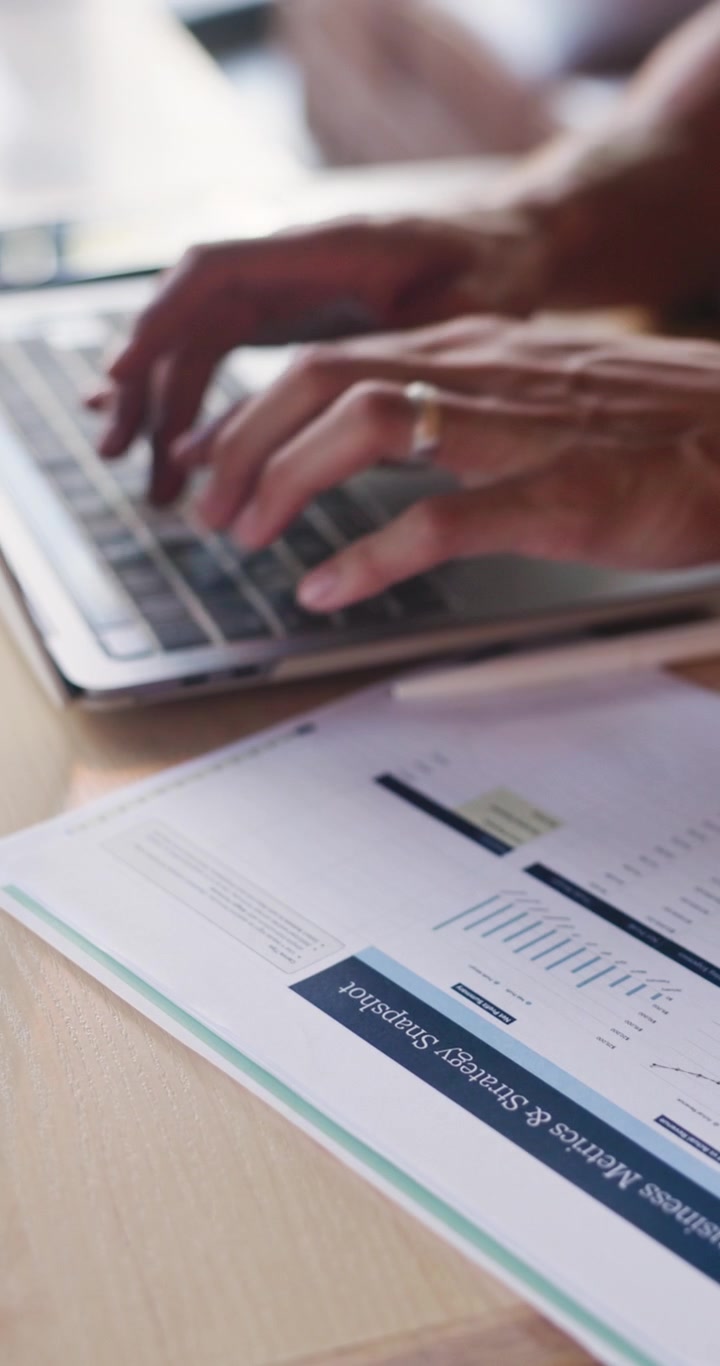 Professionista al lavoro al computer portatile con documenti di strategia aziendale