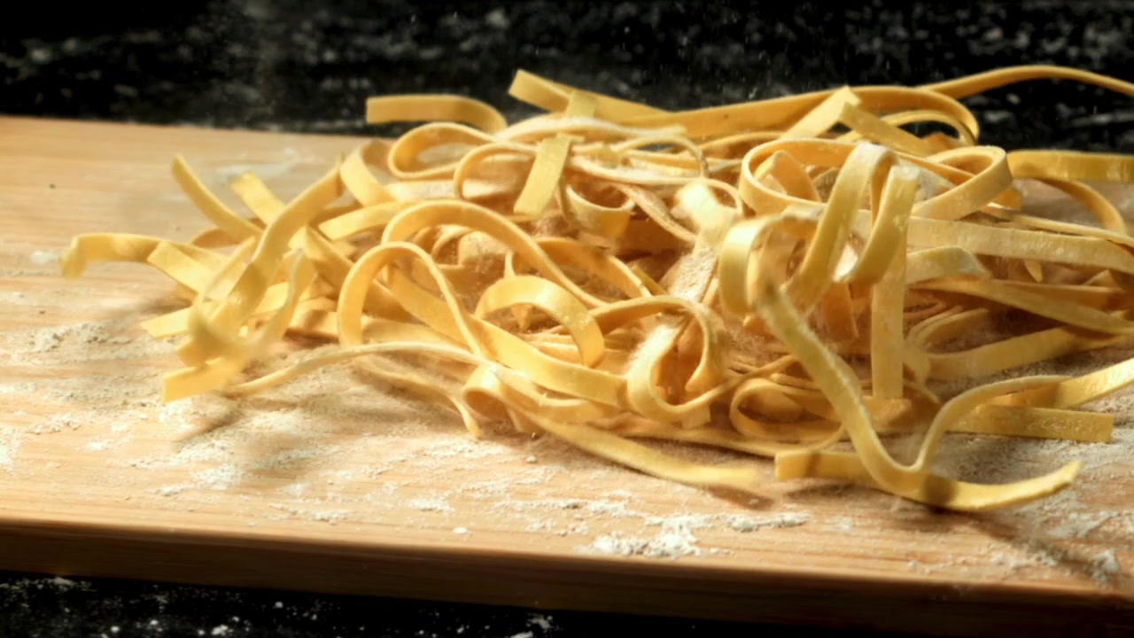Pasta fresca che cade su un tagliere infarinato al rallentatore