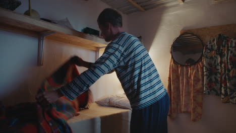 man arranging lamp in a small room at night