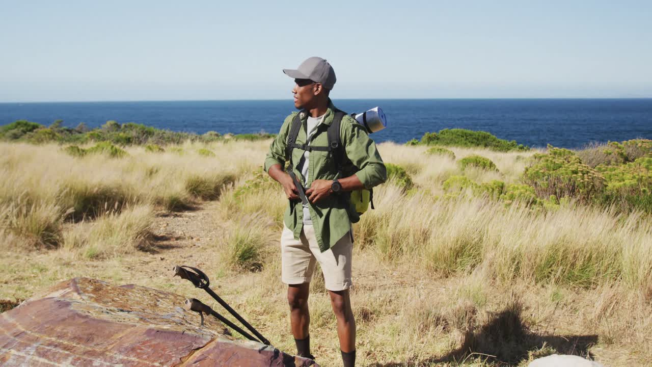 아프리카계 미국인 남자가 해안가에서 산책하며 휴식을 취하고 있습니다.