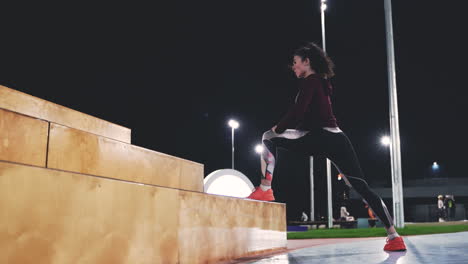 sportive curly girl doing lunges on stairs in the park at night 2