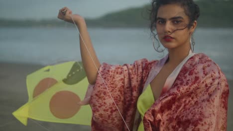 Una-Joven-Con-Ropa-Colorida-Voló-Una-Cometa-En-La-Playa-Con-La-Montaña-Al-Fondo