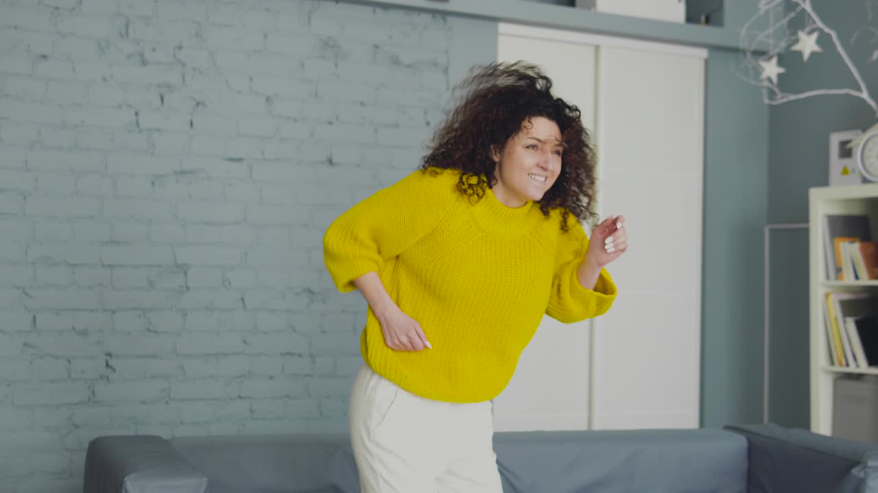 Funny positive lady in yellow sweater actively moving, dancing in her own flat