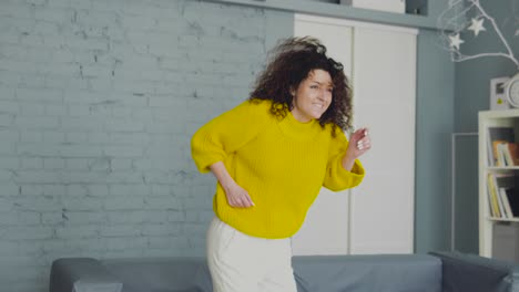 funny positive lady in yellow sweater actively moving, dancing in her own flat