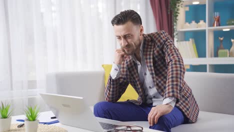 Enjoyable-and-carefree-businessman-is-using-laptop-at-home-and-is-happy.