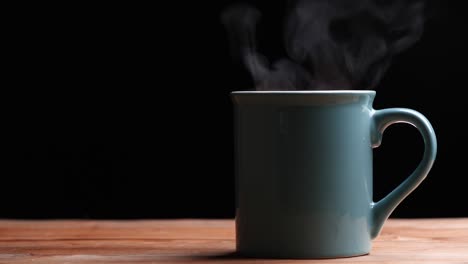 close up hot coffee cup with nature steam smoke of coffee on wooden table, black background with copy space. coffee and tea drink concept.