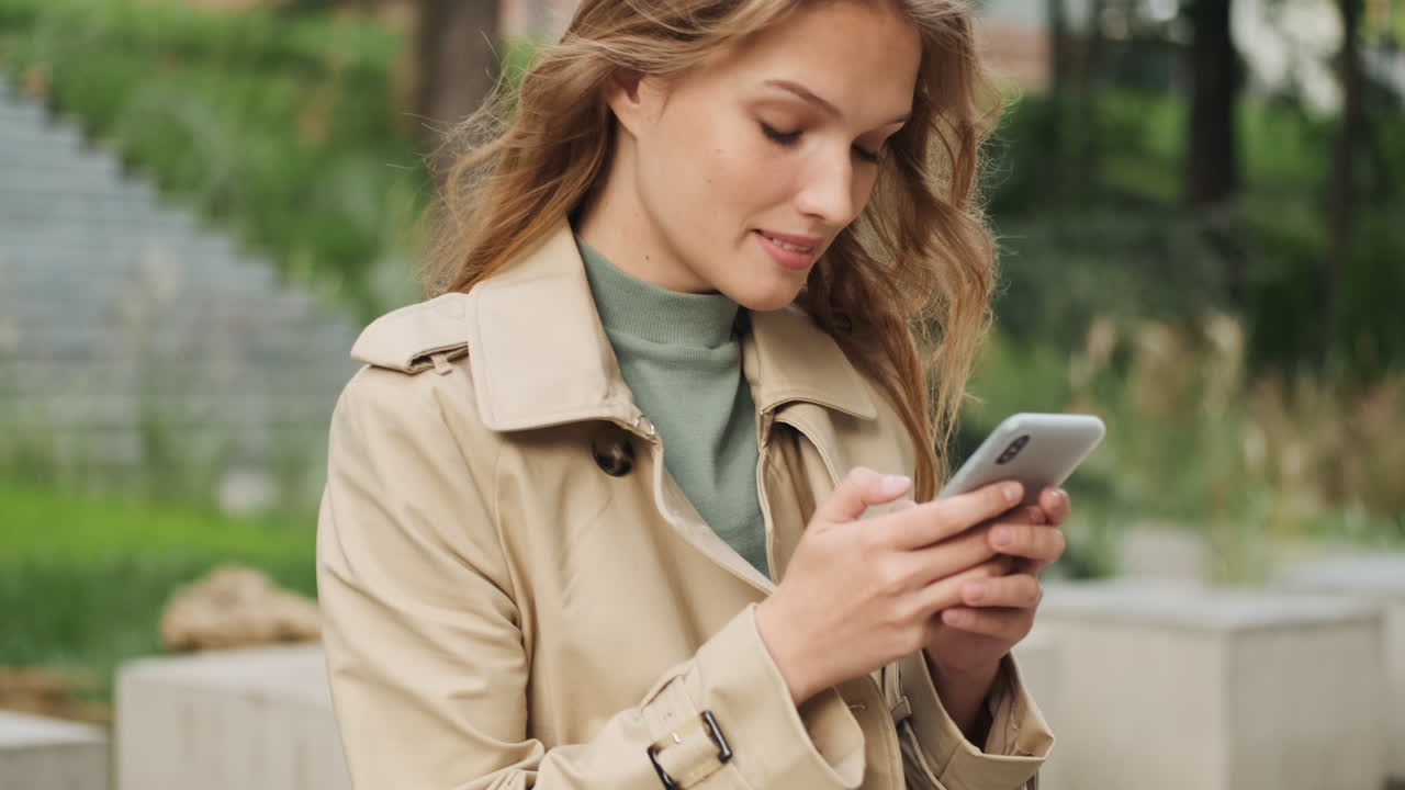 Worried Caucasian female student using smartphone outdoors.
