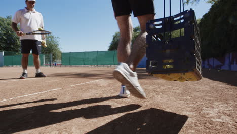 man carrying tennis balls on a tennis court