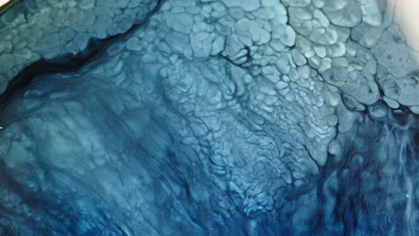 vibrant blue liquid patterns swirl and mix in intricate macro detail, creating a dynamic abstract effect
