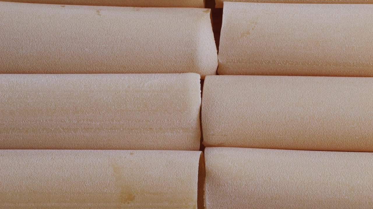 Primer plano de tubos de pasta canelones crudos sobre una superficie de madera