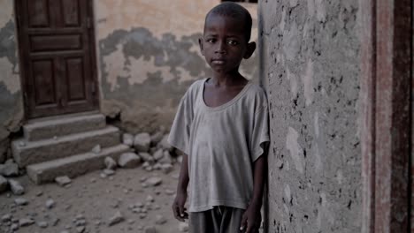 sad child leaning against a concrete wall in a poor area, wearing a worn out t shirt, captures the harsh realities of poverty and its impact on children