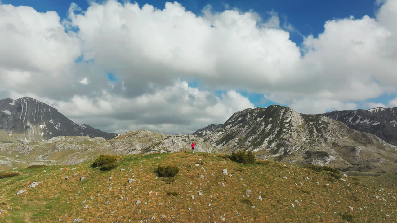 Drone orbit back of woman in front of majestic Montenegro Durmitor mountains