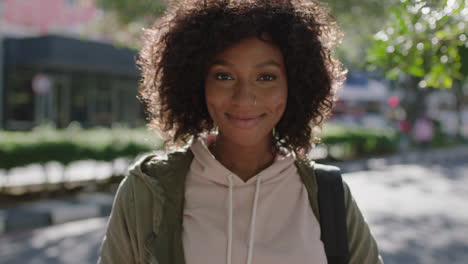 portrait of young attractive african american woman afro hairstyle smiling cheerful in city street