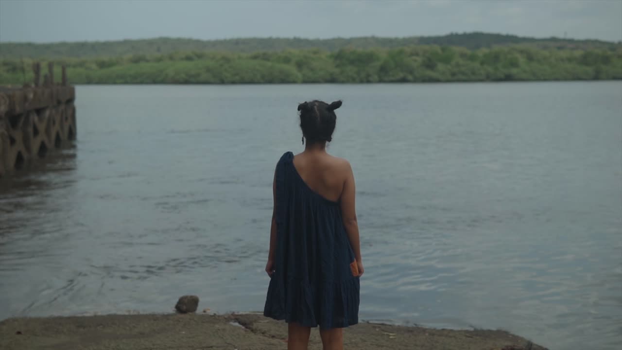 Ragazza che guarda altrove in piedi in riva a un lago - la ragazza guarda il lago assorta nei suoi pensieri - concetto di depressione, solitudine