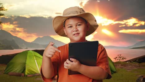 boy with tablet at sunrise campsite