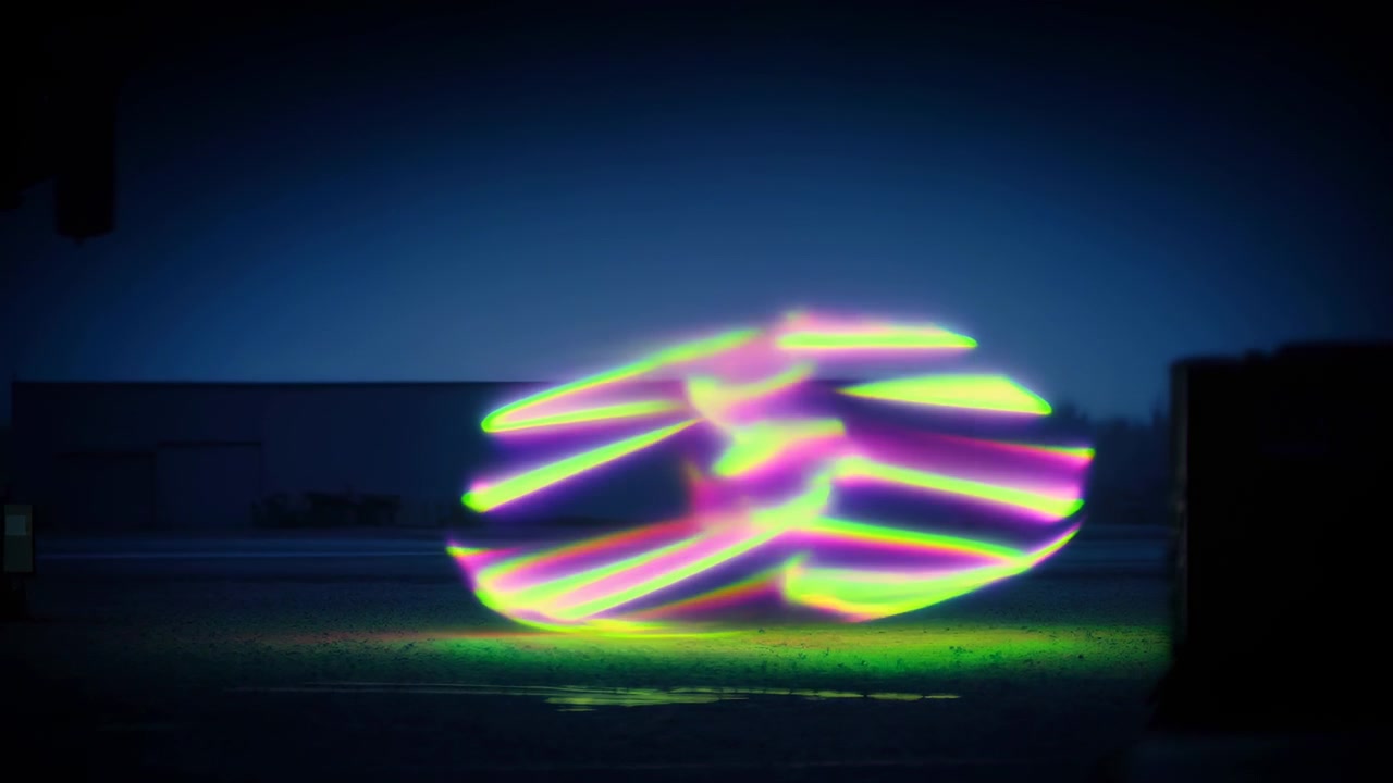 Veelkleurige neonlinten transformeren in brede gelaagde horizontale banden over natte industriële grond, creërend gestapelde lussen, heldere reflecties, zachte vervaging en levendig contrast binnen een donkere stedelijke omgeving.