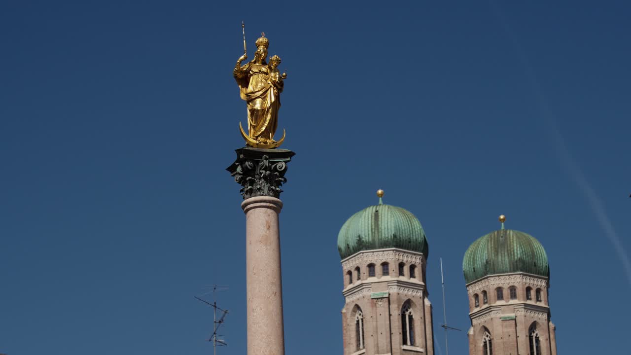 Złoty posąg Kolumny Maryjnej w Monachium z ikonicznymi kopułami Frauenkirche w tle